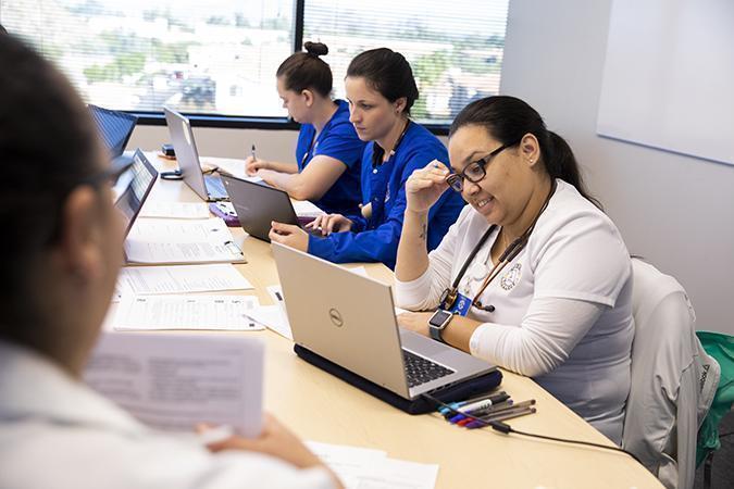 About Arizona College - A group of people sitting at a table using a laptop computer - Technology Specialist