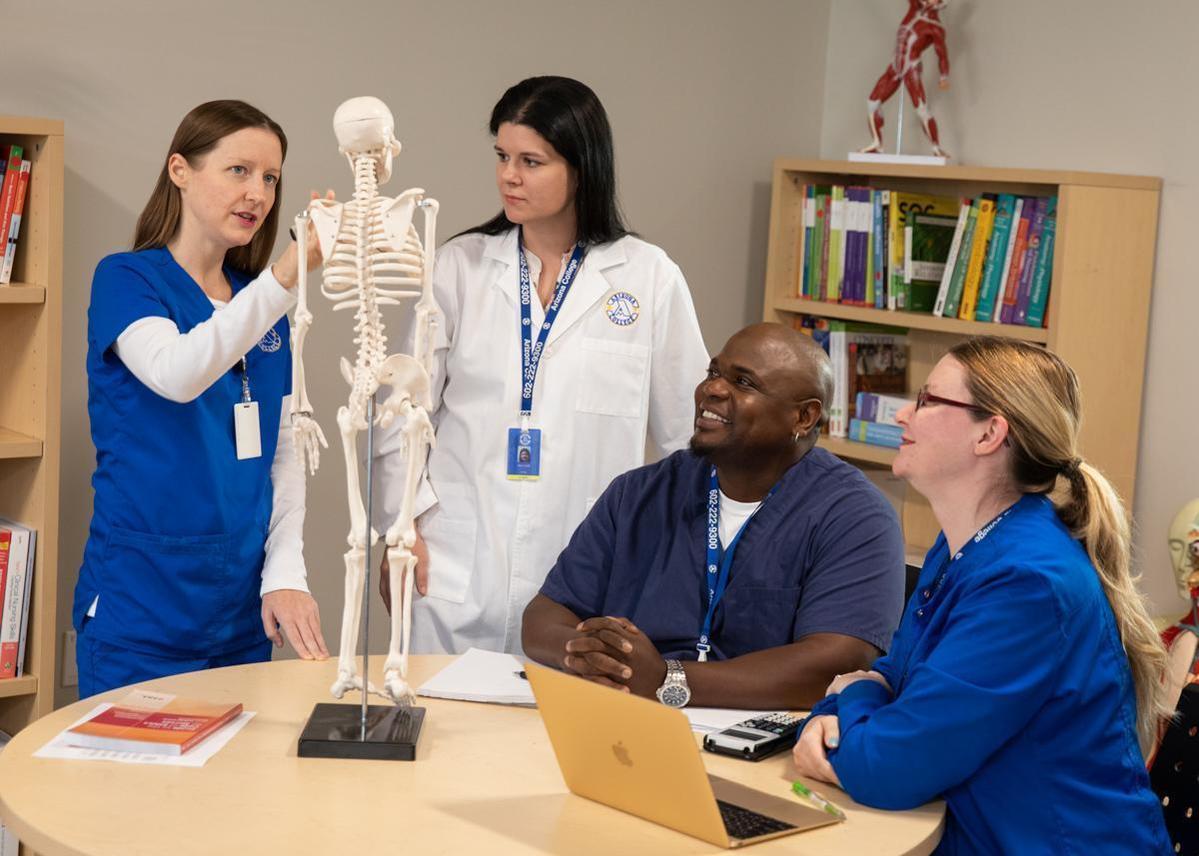 Nursing program students and faculty standing next to a book shelf at Arizona College