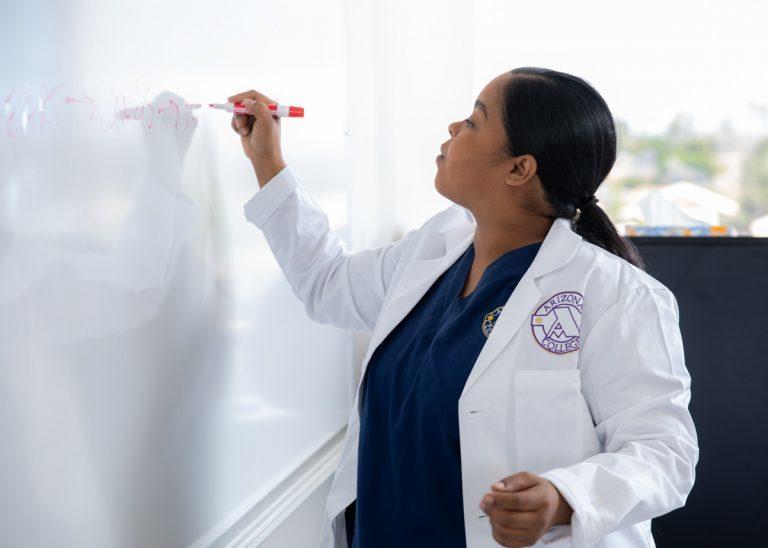 Teachers writing on the whiteboard at Arizona College