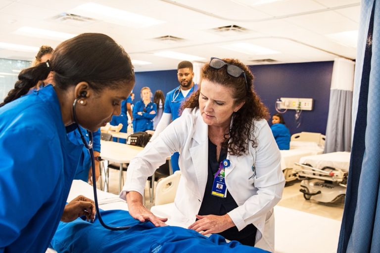 Nursing Program Faculty With Students In Nursing School Lab