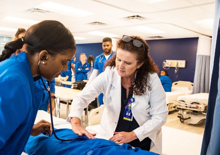 Nursing Program Faculty With Students In Nursing School Lab