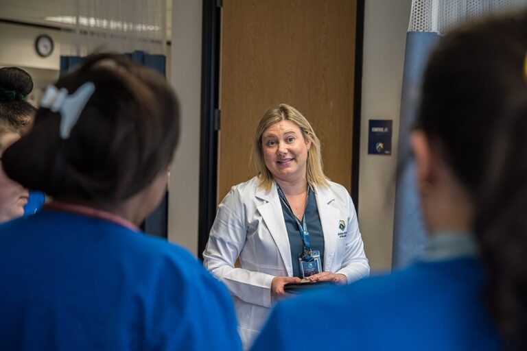 Faculty member discusses coursework with nursing students at our school.